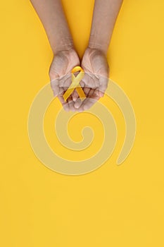 International Childhood Cancer Day. Child hands holding yellow gold ribbon. Sarcoma Awareness, Bone cancer, childhood cancer