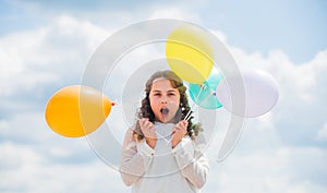 International childrens day. Happy child with colorful air balloons over blue sky background. express positive emotions