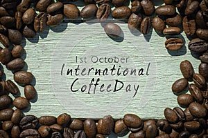 International Coffee Day inscription written on the wooden background. Roasted coffee beans on wooden background.