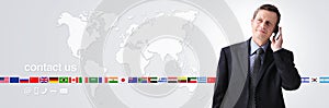 International contact us concept, businessman with mobile phone isolated on world map background, flags icons and contact symbols