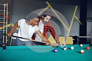 International couple playing a billiard in a club