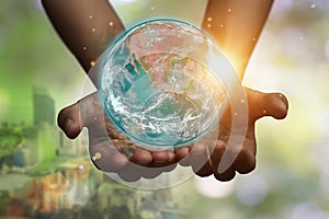 International day of forests and earth day concept: hands holding blue earth globe over and green city background for world