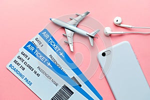 International flight concept with tickets, airplane and smartphone on a pink background