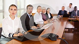 International group of business people listening to presentation at tables in meeting room