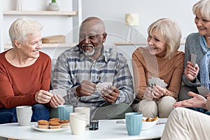 International group of cheerful elderly people chilling together, playing cards