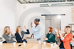 International group of happy women celebrating success at team meeting