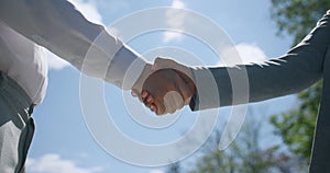 International partnership. Close up of caucasian businessman and african american business lady shaking hands over sky