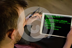 International Programmers Day. Caucasian man programs on the tablet at home. Developing programming and coding technologies.