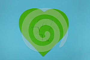 The international recycling sign Moebius loop and a heart cut out of green paper on a blue background. November 15 is