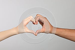International relationships. People making heart with hands on light grey background, closeup
