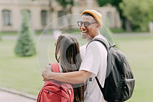 International students couple walking to the university building hugging each other, wearing stylish clothes