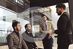 An international team of successful young business men in suits at a meeting are discussing the implementation of