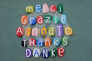 International thanks in different languages with stone colored letters over green sand photo