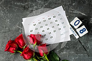 International Womans day concept with calendar pages of year 2021 of march and red roses on gray background