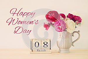 International women day concept with beautiful flowers in the vase and date on wooden table.