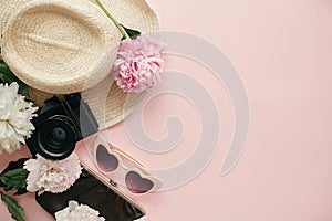 International Women`s Day flat lay. Stylish girly image of peonies, photo camera, retro sunglasses, hat, purse on pastel pink