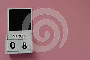 International Women's Day.March 8. Wooden calendar on pink paper background. Copy space.Side view.