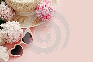 International Women`s Day. Stylish girly pink retro sunglasses, white and pink peonies, straw hat on pastel pink paper with copy