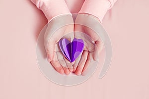 International world epilepsy illness awareness day. Kid girl hands holding small violet purple paper heart. Support, care and