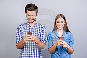 Internet addicted. Two young lovers are busy at their mobile phones in social nets, wearing casual shirts, isolated on pure