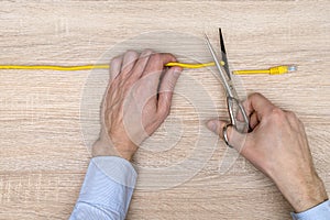 Internet censor cutting a yellow network cable  over wooden background