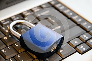 Internet and computer systems security concept: blue padlock closed on top of laptop computer keyboard