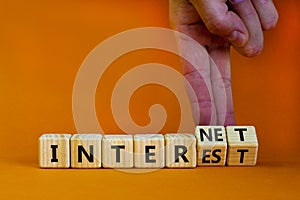 Internet and interest symbol. Businessman turns wooden cubes and changes the words interest to internet. Beautiful orange