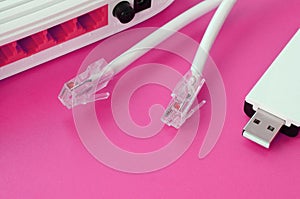 Internet router, portable USB wi-fi adapter and internet cable plugs lie on a bright pink background. Items required for internet