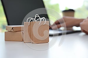 Internet shopping. Small bags and boxes near woman using laptop indoors, space for text