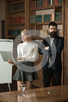 Internet surfing concept. Pretty woman and bearded man perform internet surfing on laptop. University students use