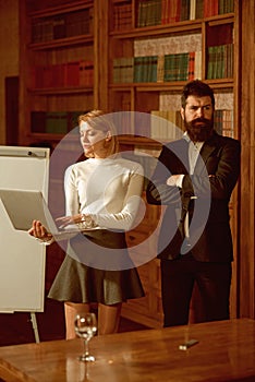 Internet surfing concept. Pretty woman and bearded man perform internet surfing on laptop. University students use