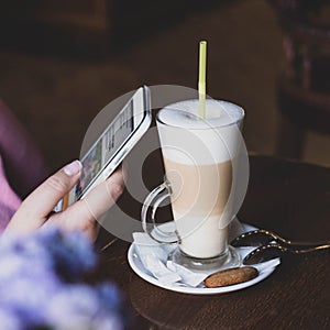 Internet surfing. A girl in a cafe over a cup of coffee reads news on social networks. Mobile Internet 4G, 5G