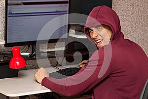 Internet troll with the evil face sitting at the computer. Very bad man laughs wickedly writing nasty things on the forum photo