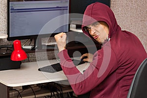 Internet troll with the evil face sitting at the computer. Very bad man rejoices writing nasty things on the forum photo