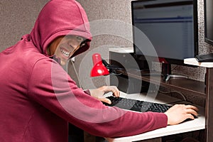 Internet troll with the evil face using a computer. Very bad man laughs wickedly writing nasty things on the forum photo