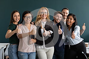 Interns and aged ceo looking at camera showing thumbs up