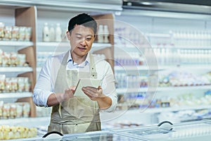 Internship at work. A young man, an Asian stager,student, an assistant works in a supermarket