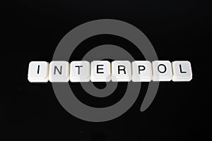 Interpol text word title caption label cover backdrop background. Alphabet letter toy blocks on black reflective background. White