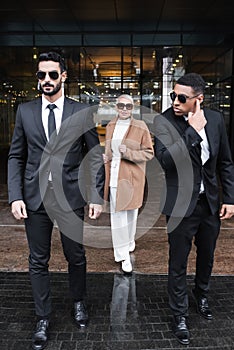 interracial bodyguards in sunglasses escorting stylish