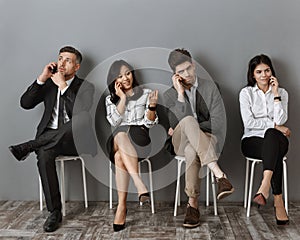 interracial business people talking on smartphones while waiting