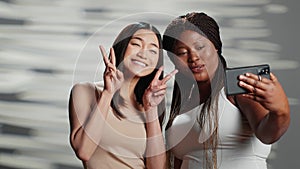 Interracial confident girls taking pictures on smartphone