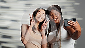 Interracial confident girls taking pictures on smartphone