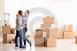 Interracial couple with carton boxes in room. Moving into new house photo