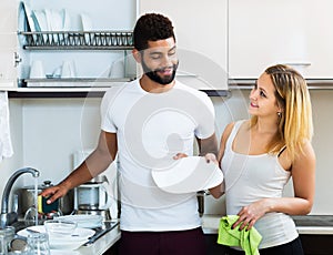 Interracial couple cleaning in the kitchen