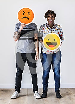 Interracial couple holding an expressive emoticon face facial expression frown and smile relationship issue concept