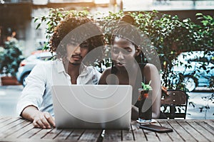 Interracial couple with laptop in street cafe