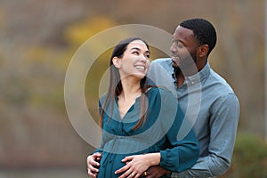 Interracial couple looking each other enjoying pregnancy