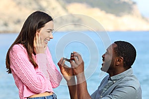 Interracial couple proposing marriage on the beach photo