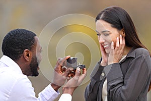 Interracial couple proposing marriage in a park