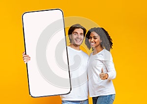 Interracial couple showing big white empty smartphone screen and like